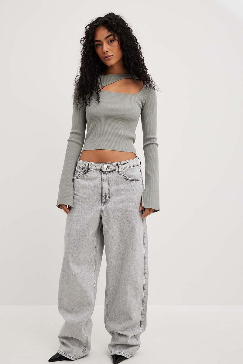 Relaxed-fit light grey denim jeans on a young female model with curly dark hair, wearing a grey crop top in front of a plain background.