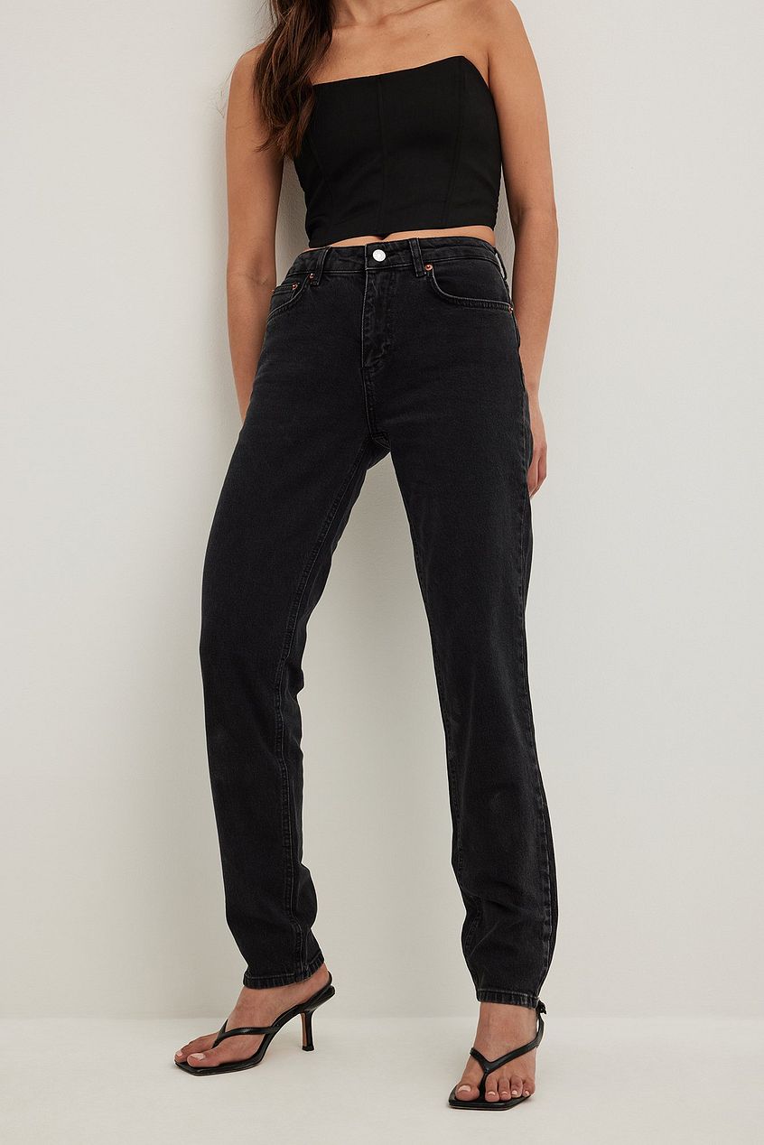 Slim mid-waist black denim jeans on female model, featuring a strapless black crop top