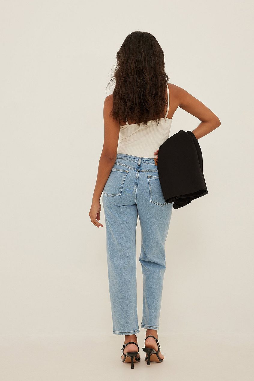 Mid Waist Slim Leg Jeans in a neutral background, showcasing a female model wearing the denim product.