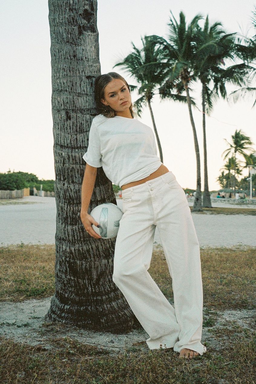 Low Waist Pocket Detail Denim: Woman in white casual outfit leaning against palm tree in tropical setting