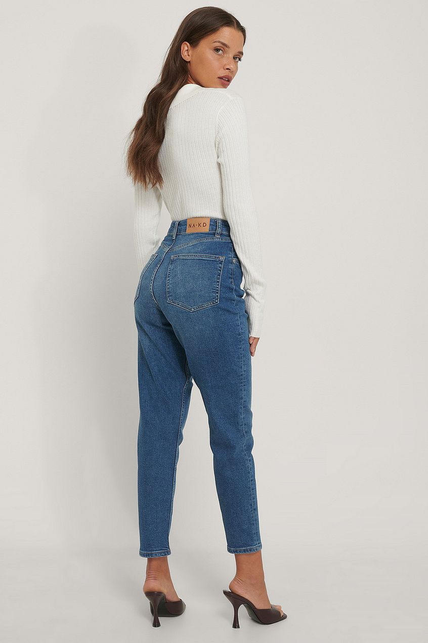 Elegant woman modeling organic mom jeans from Ace Cart, featuring a relaxed straight leg silhouette and classic denim construction.