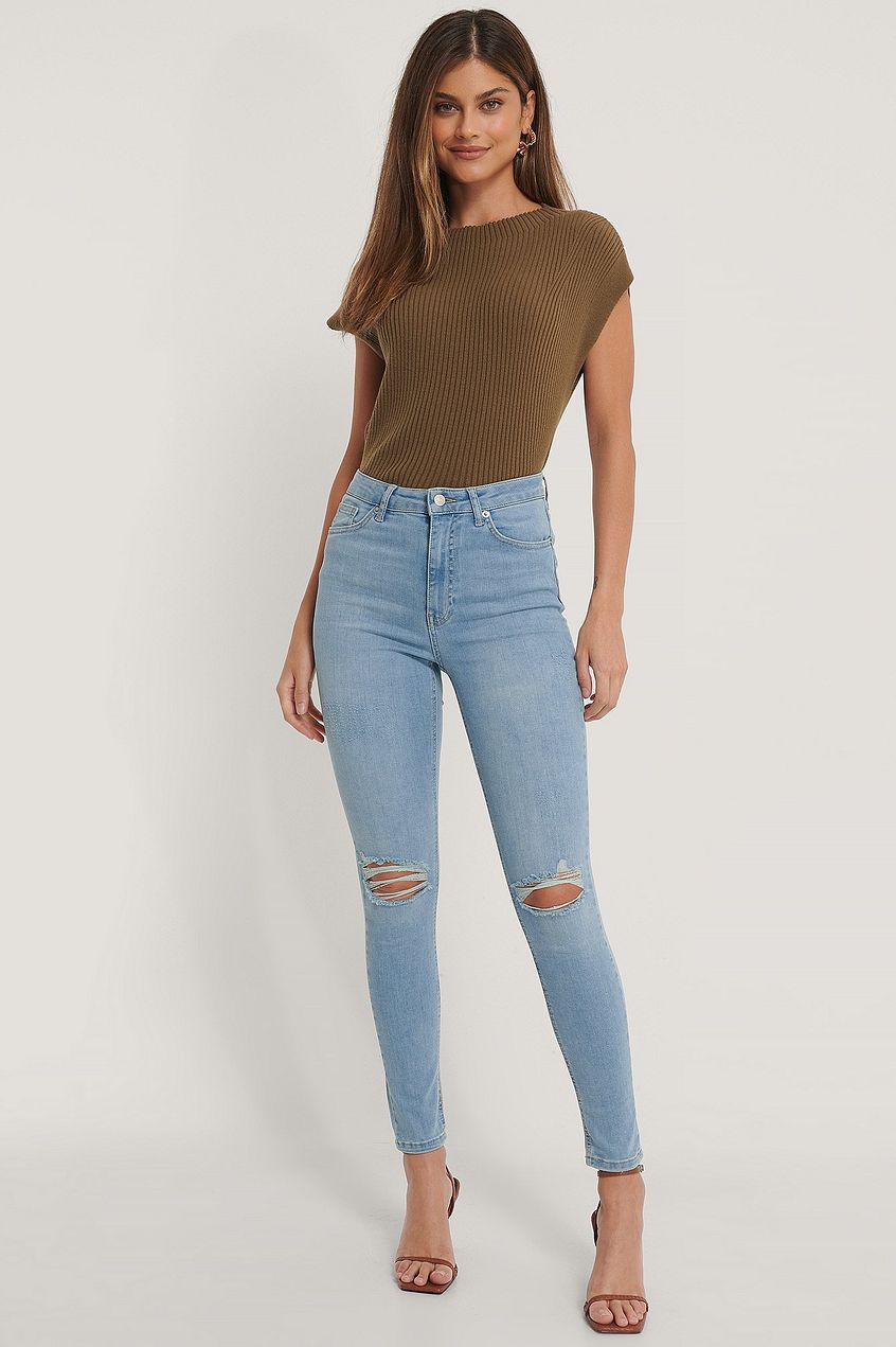 Distressed high-waisted skinny jeans paired with a ribbed olive green top, showcasing a trendy and casual fashion look.