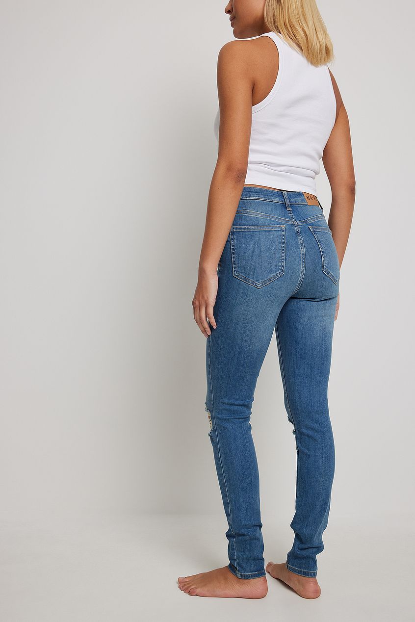 Skinny high waist destroyed denim jeans, featuring a slim silhouette and distressed detailing, presented on a white background.