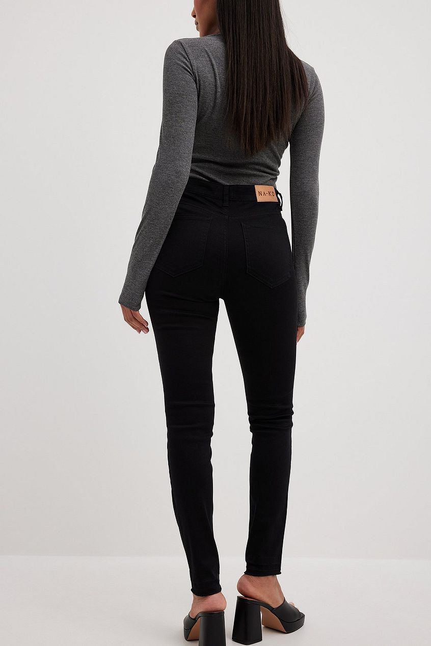Skinny high-waist black jeans with open hem, worn with a grey long-sleeved top, showcasing a stylish and casual fashion look.