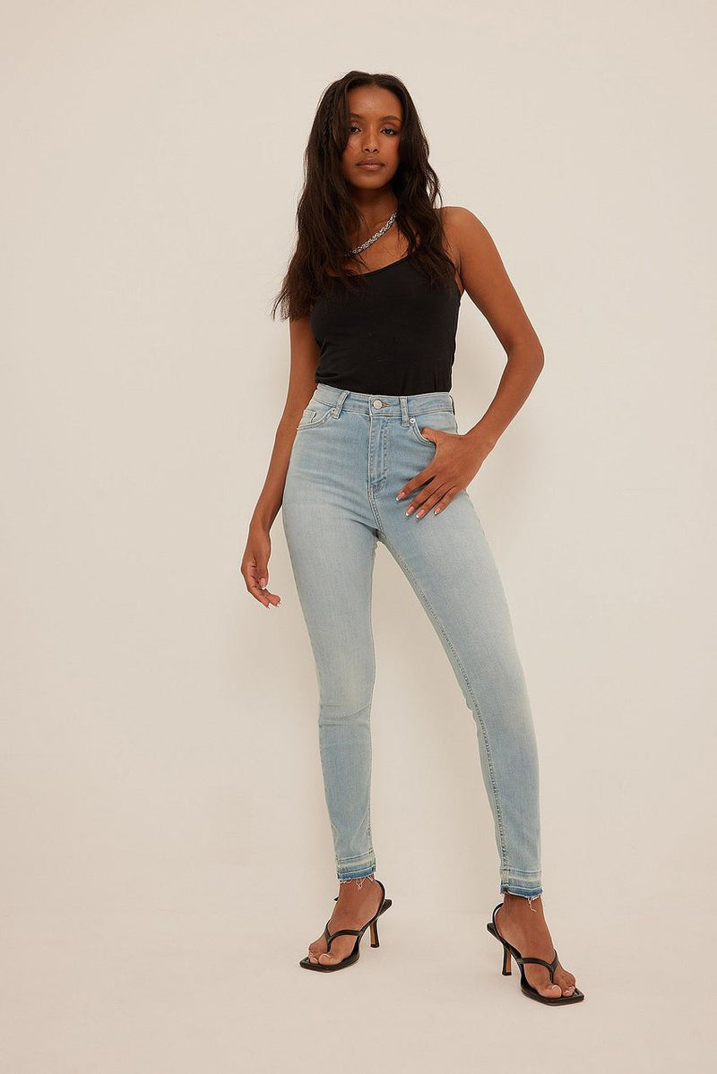 Skinny high-waist open-hem light wash denim jeans, worn by a young woman with long dark hair against a plain background.