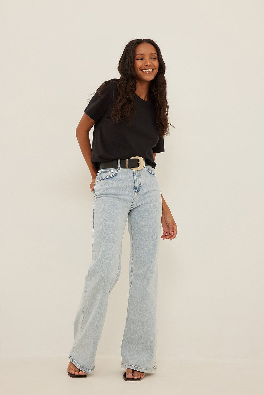 Relaxed bootcut fit jeans, black top, and smiling woman against white background