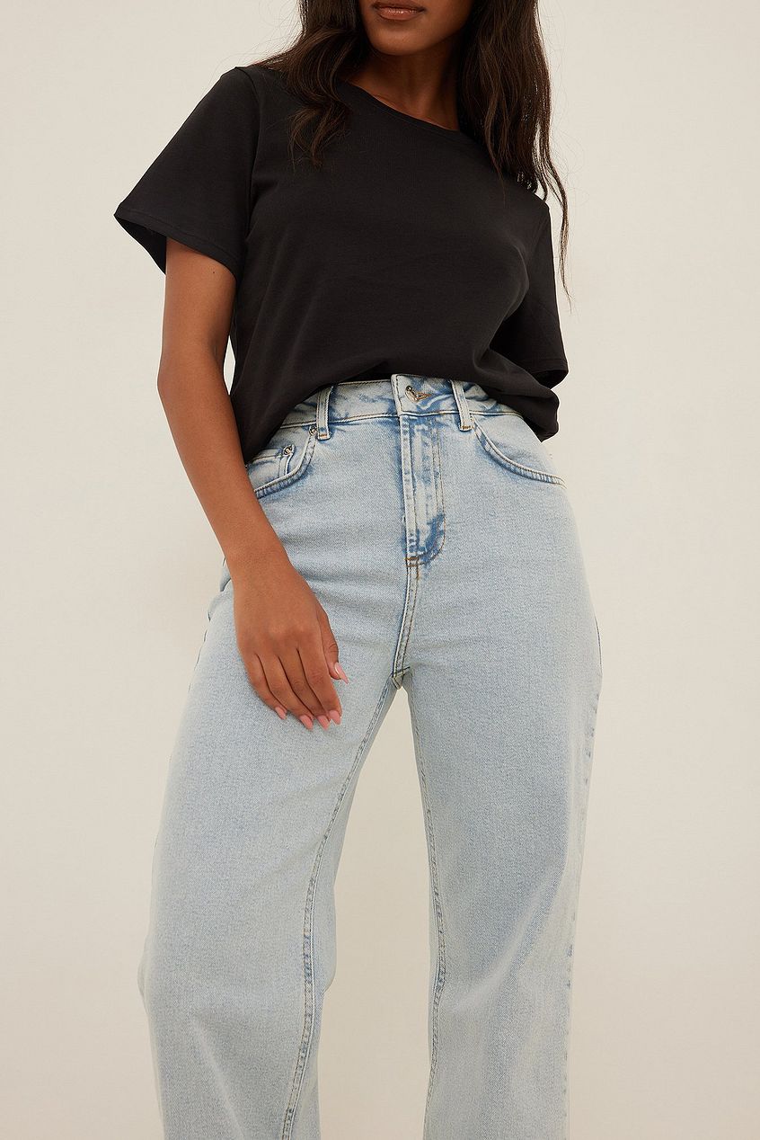 Relaxed bootcut fit denim jeans, high-waisted with light blue wash, paired with a classic black t-shirt for a casual, stylish look.