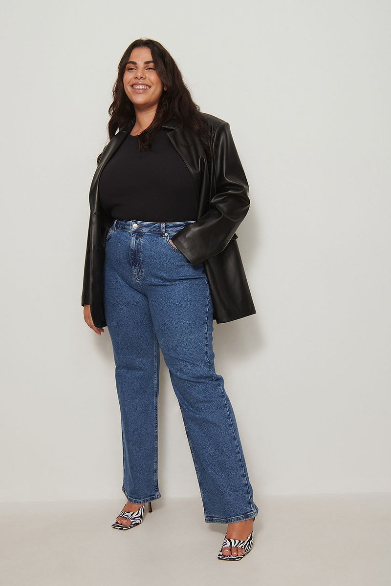 Relaxed fit recycled jeans, black leather jacket, smiling woman posing in white background