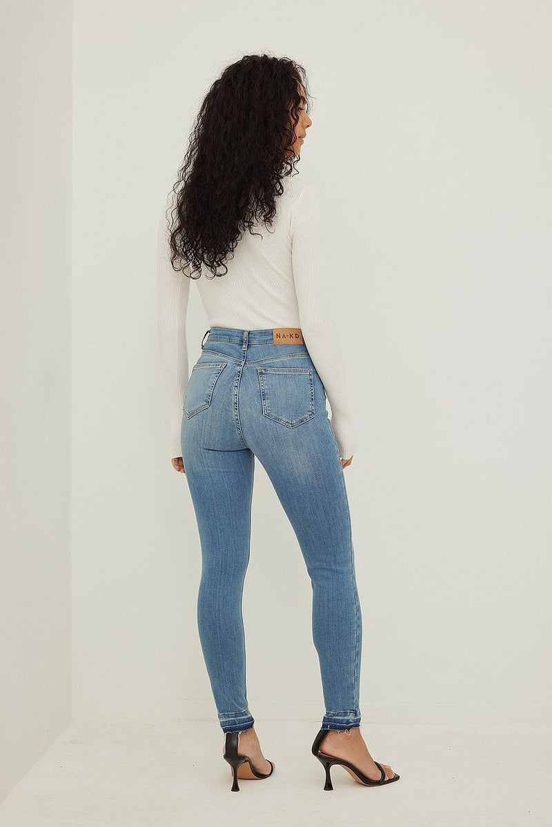 Skinny high-waist open hem denim jeans with relaxed fit on female model.