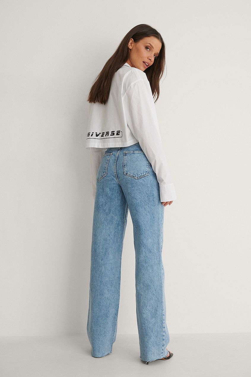 High-waist straight-fit raw-hem denim jeans with woman wearing white printed top against plain background.