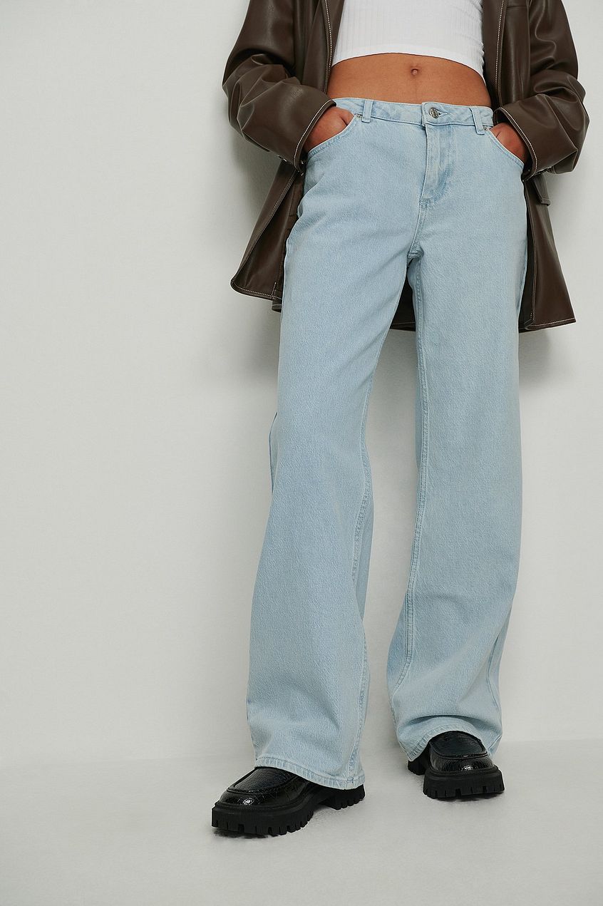 Light blue super low waist jeans worn with a brown leather jacket, showcasing a casual, fashionable style.