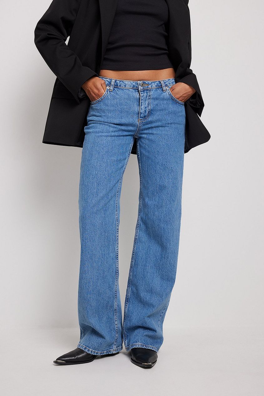 Super low waist blue denim jeans displayed on model wearing black jacket.