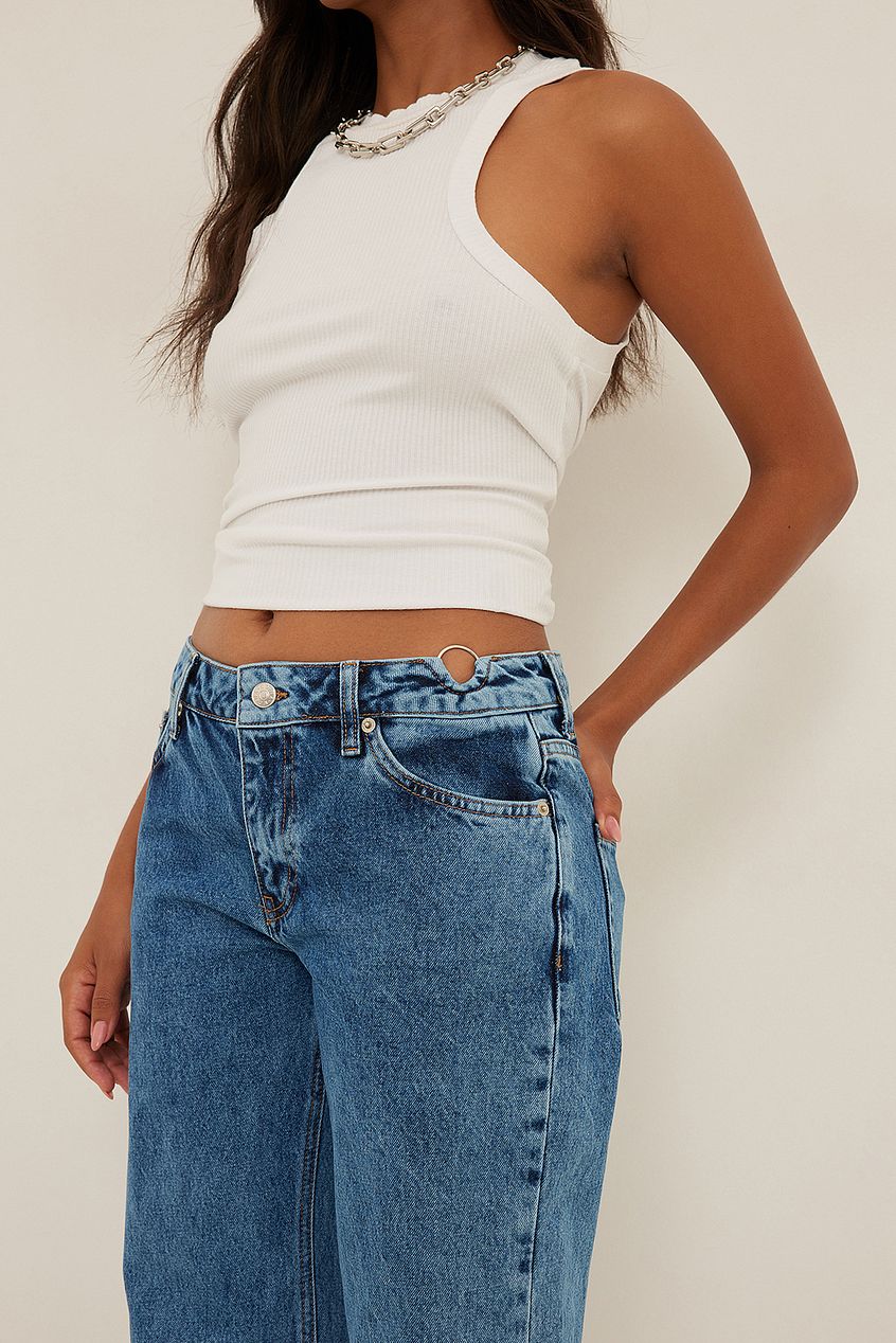 Sleeveless white crop top with lace trim, paired with high-waisted blue denim jeans on model