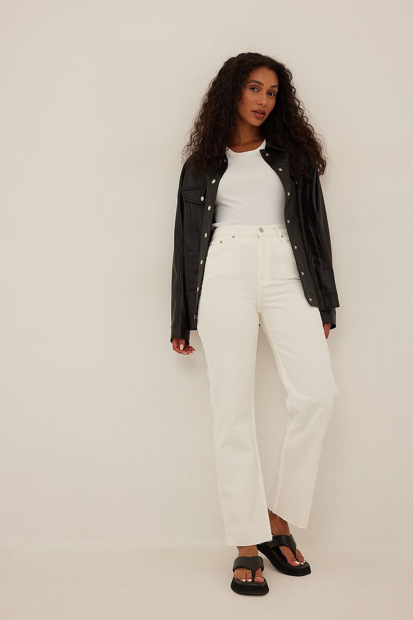 Wide Leg Cropped Denim: High-waist, relaxed fit white jeans modeled by a woman with curly dark hair wearing a black leather jacket.