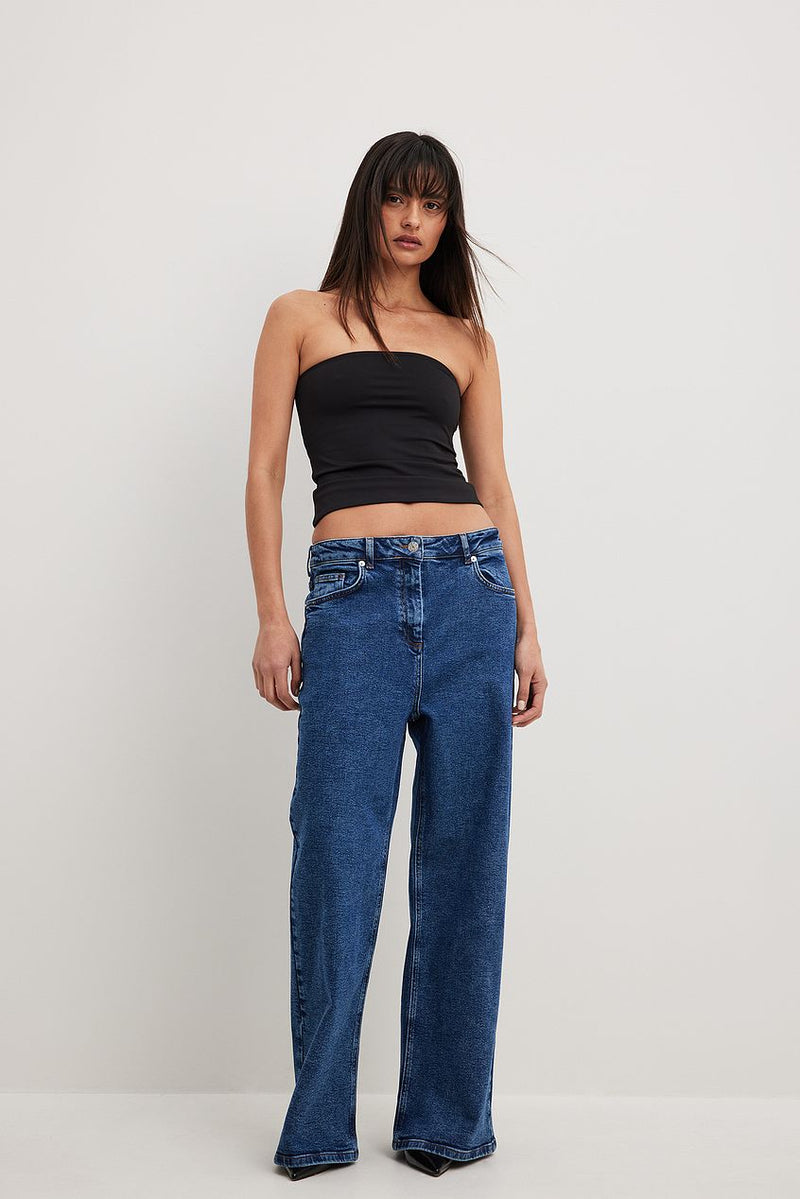 Oversized Denim: High-waisted, relaxed fit blue jeans with flared legs, paired with a black strapless top.