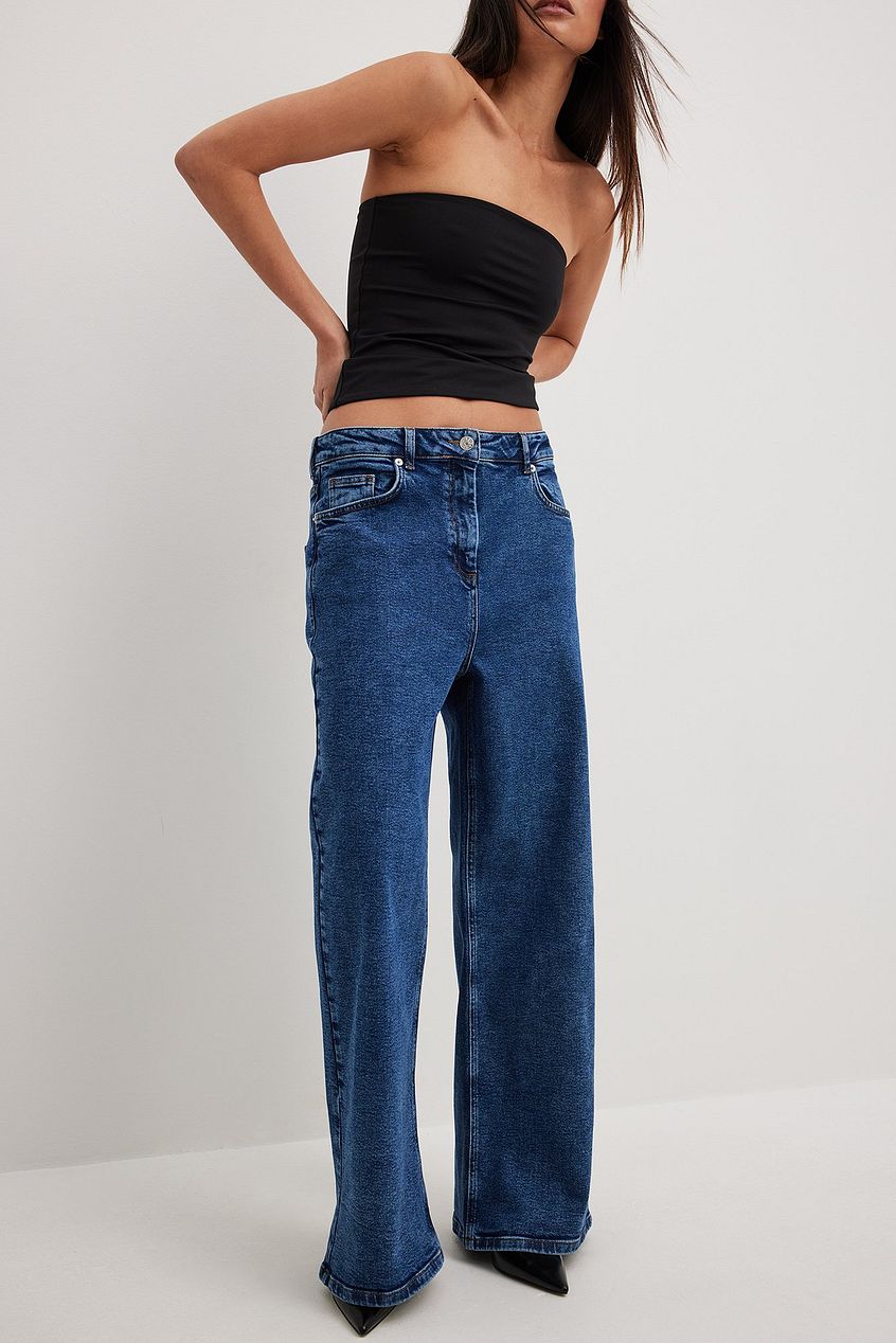 Oversized denim jeans with a black strapless crop top, modeled on a woman with long dark hair.