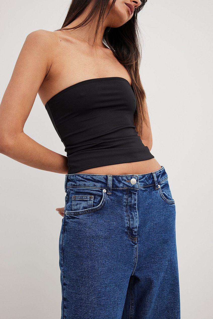 High-waist denim jeans with flared legs, paired with a black strapless top.