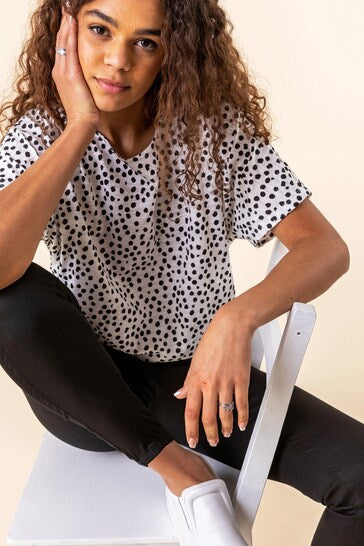 Stylish polka-dot top, comfortable black jeggings, casual sneakers - a trendy, versatile outfit showcased by a confident young woman.