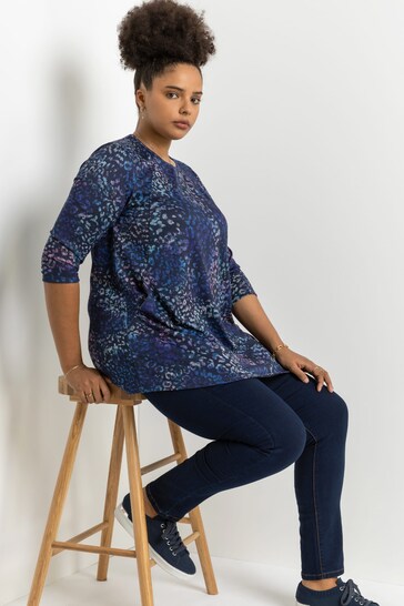 Stylish plus-size woman wearing navy floral print top and dark wash jeggings, showcasing modern curvy fashion.