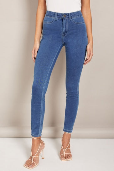 Stylish high-waisted blue jeggings with ripped knee details, worn by a woman posing against a plain background.
