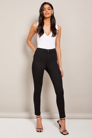 Stylish high-waisted black jeggings with a white tank top, showcasing a chic and modern fashion look.