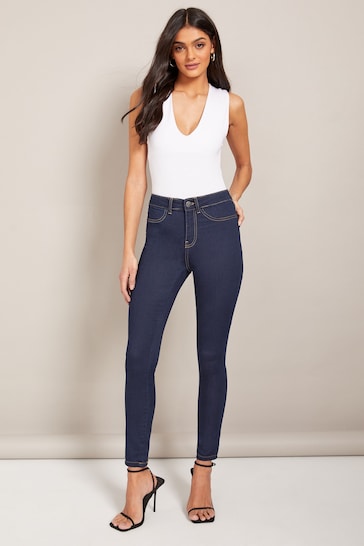 Stylish high-waisted dark blue jeggings with a white sleeveless top, showcasing a trendy casual outfit.