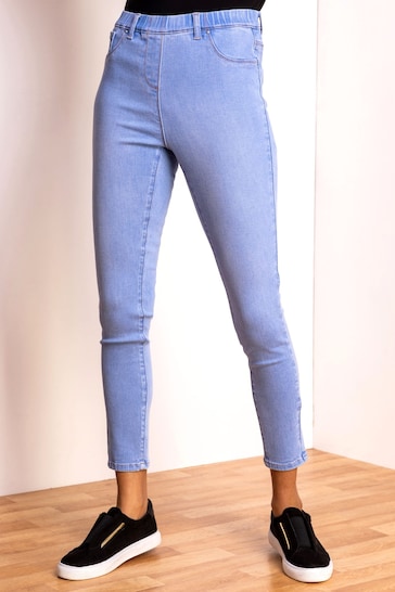 Light blue high-waisted stretch jeggings with elastic waistband, displayed on a wooden floor.