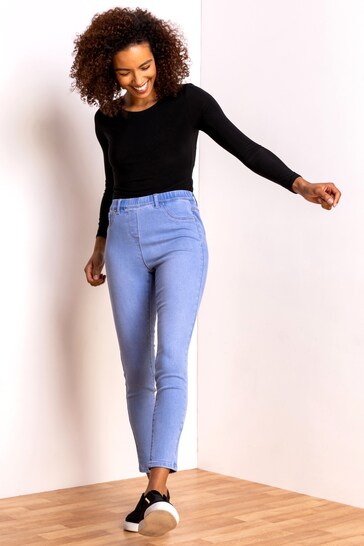 Curvy female model wearing Ace Cart's Roman Ultimate Stretch Jeggings in a light denim color, posing against a white background.