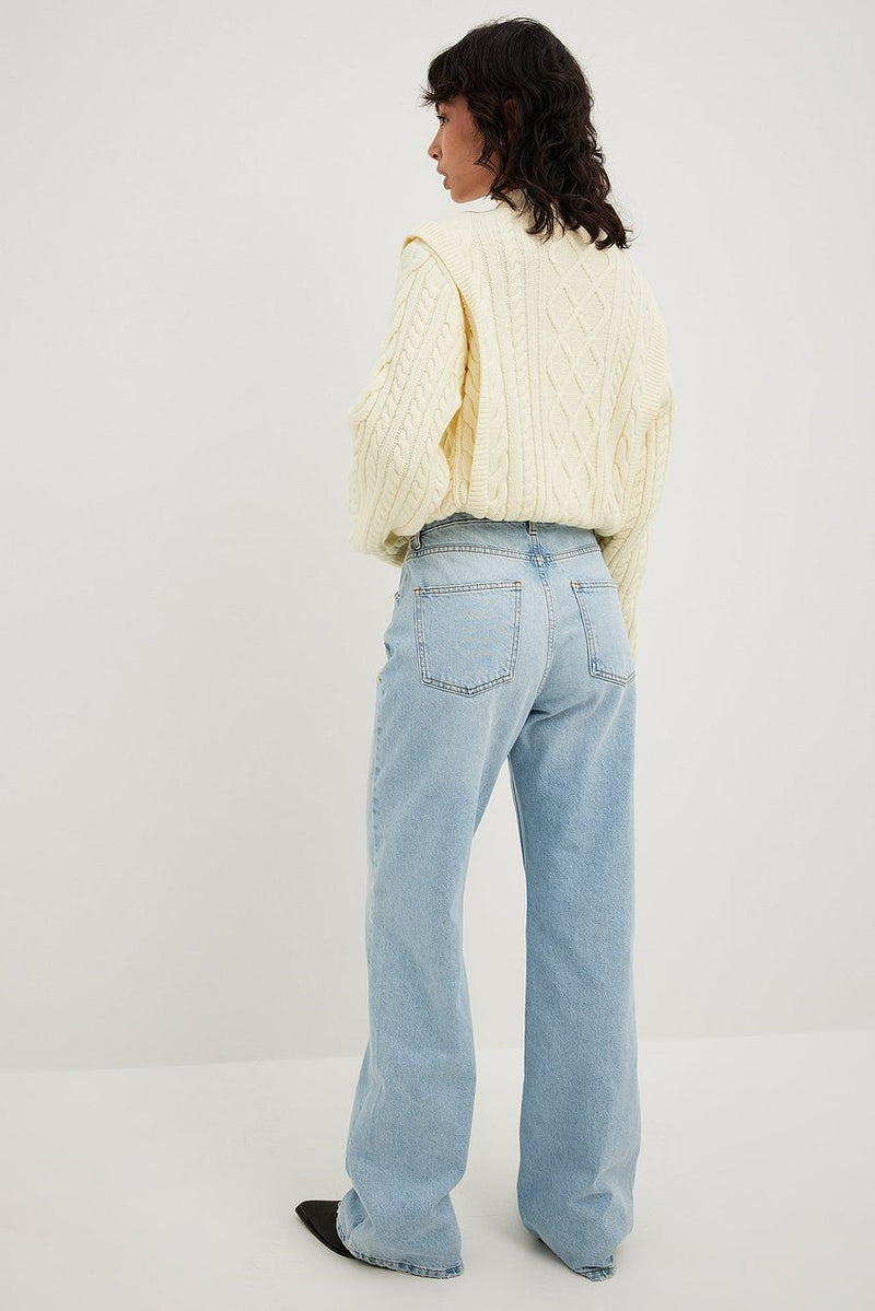 Relaxed full length denim jeans with a cozy white cable knit sweater against a plain white background.