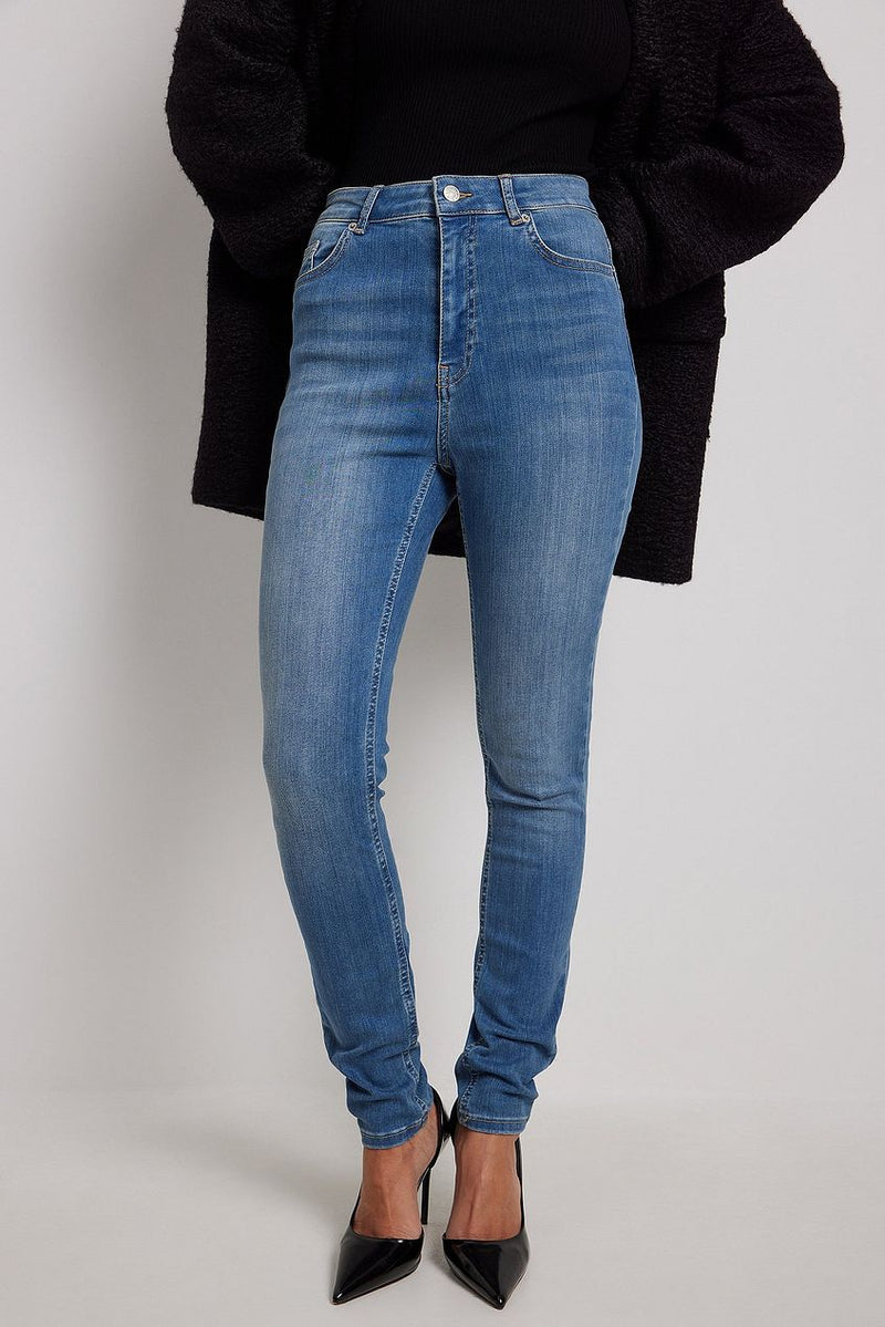 Skinny high-waist stretch denim jeans with classic five-pocket design, worn with black jacket.