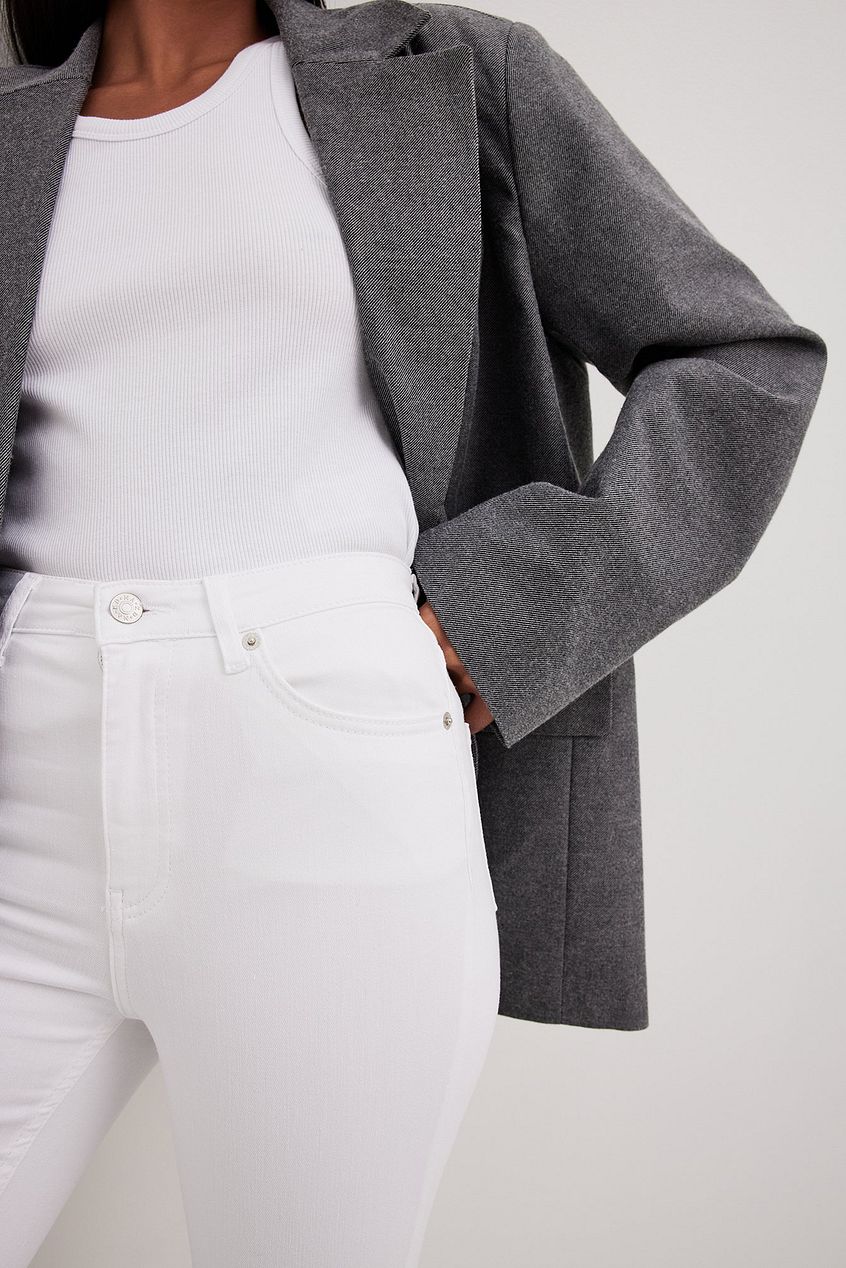 Skinny high-waist raw-hem gray jeans from Ace Cart, paired with a white top and gray coat, creating a stylish, modern look.