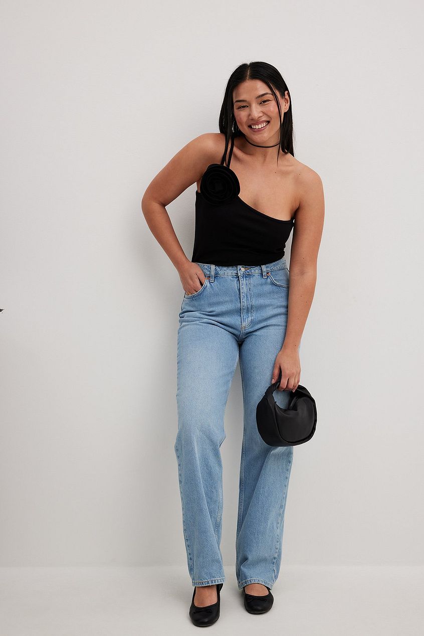 Sleek black one-shoulder top, high-waisted blue denim jeans, stylish outfit for confident young woman.