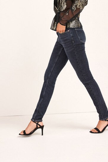 Comfortable high-waisted skinny jeans with stretchy fabric, featuring a dark wash and stylish ripped details, displayed on a model's legs in the image.