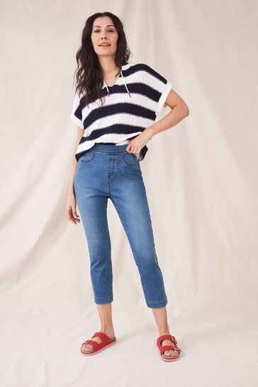 Fashionable striped top, high-waisted cropped blue jeans, and red sandals showcased on female model