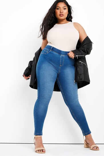 Fashionable mid blue skinny jeggings with stretch fabric, worn by a confident woman with long dark hair.