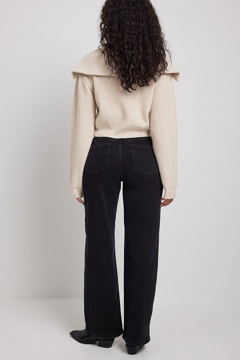 Wide leg black denim jeans with beige ribbed crop top, shown on model with curly dark hair.